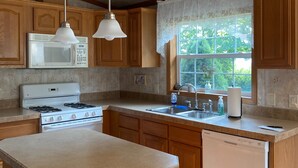 Une cuisine avec des meubles de rangement en bois, une cuisinière blanche, un four à micro-ondes, un évier et un lave-vaisselle.