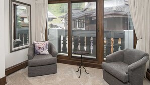 A cozy room with two grey armchairs, a small round table, and a large window with a view of traditional buildings. - 5 Bedroom in the Heart of Vail Village (Vail)