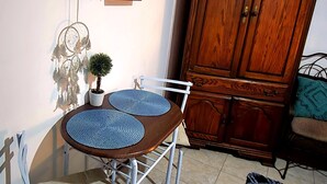 Un comedor con mesa, sillas, un armario y un estante en la pared.