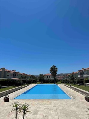 A rectangular swimming pool with a clear blue water surface, surrounded by a stone-tiled deck.