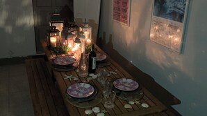 Un tavolo da pranzo apparecchiato con piatti, bicchieri e candele, circondato da lanterne e una piccola riproduzione di un villaggio.