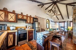 Uma cozinha com armários de madeira, fogão, forno e uma área de refeições com mesa e cadeiras.