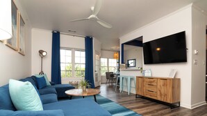 Un salon moderne avec un canapé bleu, une table basse en bois et un ventilateur de plafond.
