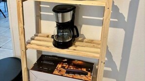 A wooden shelf with three coffee makers and a box.
