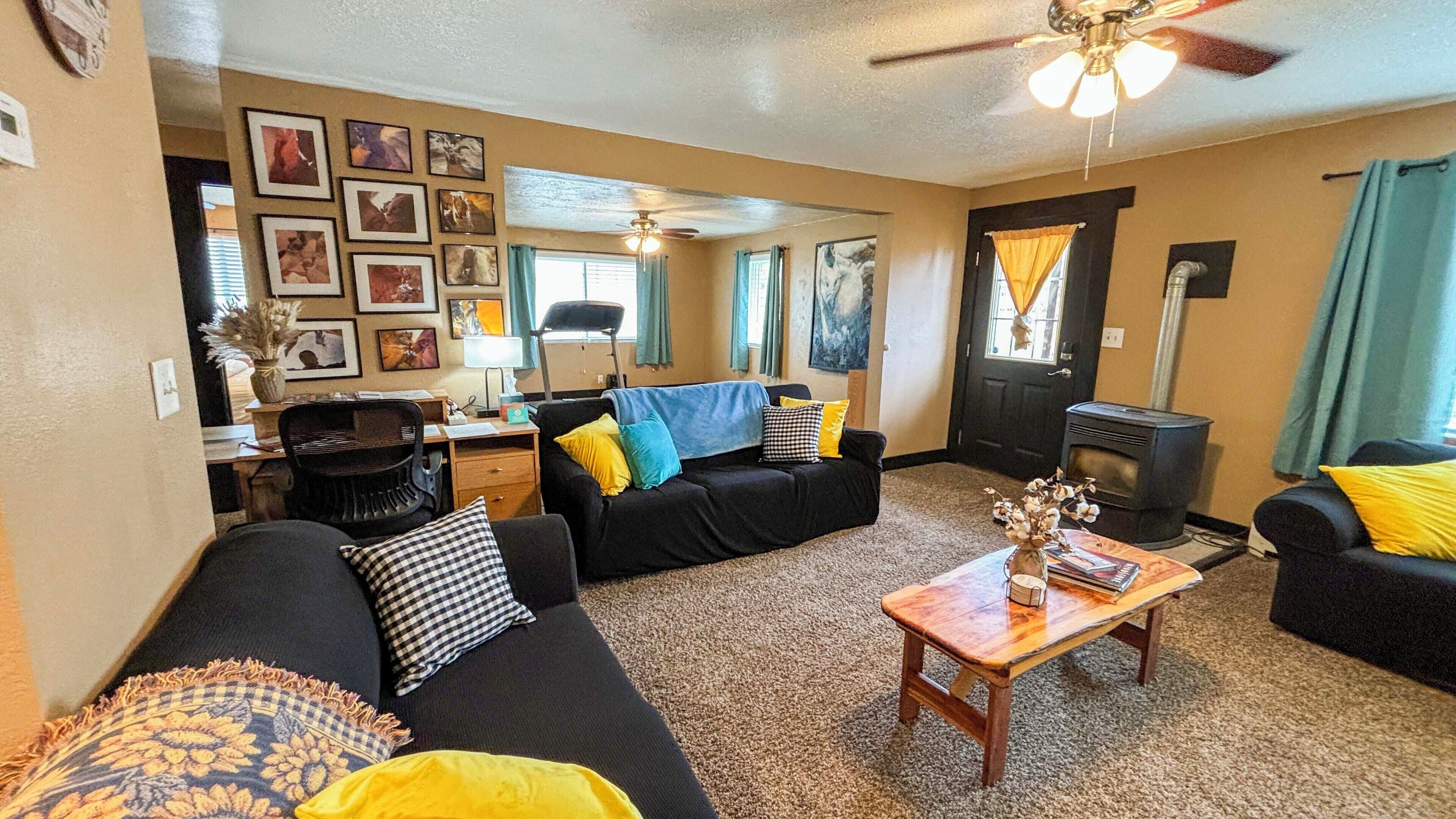 A living room with a sofa, a coffee table, a fireplace, and a ceiling fan.