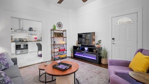 Un salon moderne comprenant un canapé, une table basse, un téléviseur et une bibliothèque.