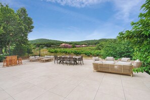 Relax in a serene outdoor space surrounded by lush greenery and a hilly landscape.