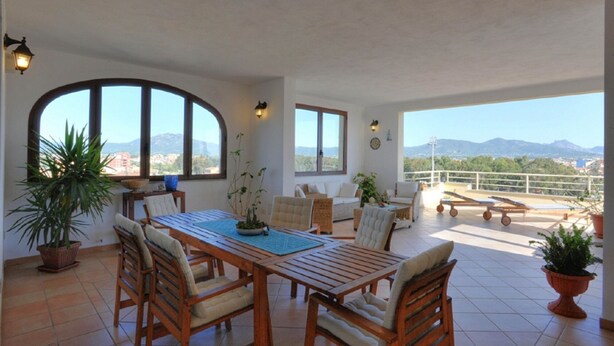 Un patio spazioso con zona pranzo, ampie finestre e vista sulle montagne.