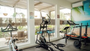 Une salle de sport équipée de divers appareils d’exercice, dotée de grandes fenêtres et offrant une vue sur l’extérieur.