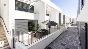 Een modern gebouw met een overdekt terras, een trap en een smal pad.