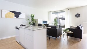 Een moderne woonkamer met een bank, een salontafel en een eethoek met stoelen.