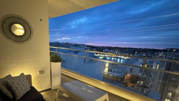 A balcony with a view of a cityscape at dusk. - Marsascala Sea View Apartment Hpi9934 (Marsaskala)