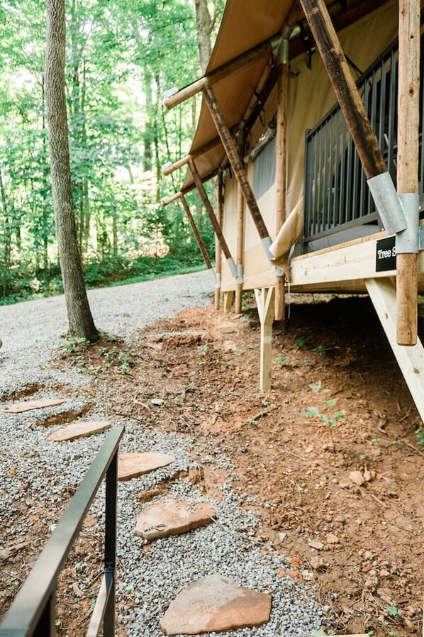 A rustic wooden structure with a covered porch, a gravel path leading to it, and a sign reading "Tree S".