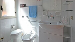 A modern bathroom with a toilet, bidet, sink, and mirror. - Villetta Santa Lucia con patio e giardino by Wonderful Italy (Cefalù)