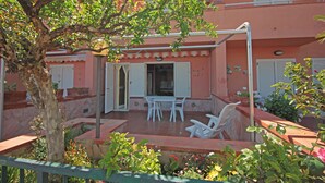 A building with a patio area featuring a table and chairs, a tree, and potted plants. - Villetta Santa Lucia con patio e giardino by Wonderful Italy (Cefalù)