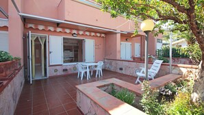 A patio with a table and chairs, a stone planter, and a lamp post. - Villetta Santa Lucia con patio e giardino by Wonderful Italy (Cefalù)