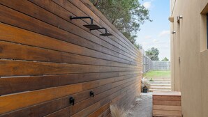 Ein Holzzaun mit Metallbeschlägen, ein Kiesweg und eine Holzterrasse.