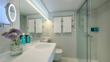 A modern bathroom with a glass shower enclosure, a white sink, and a large mirror.