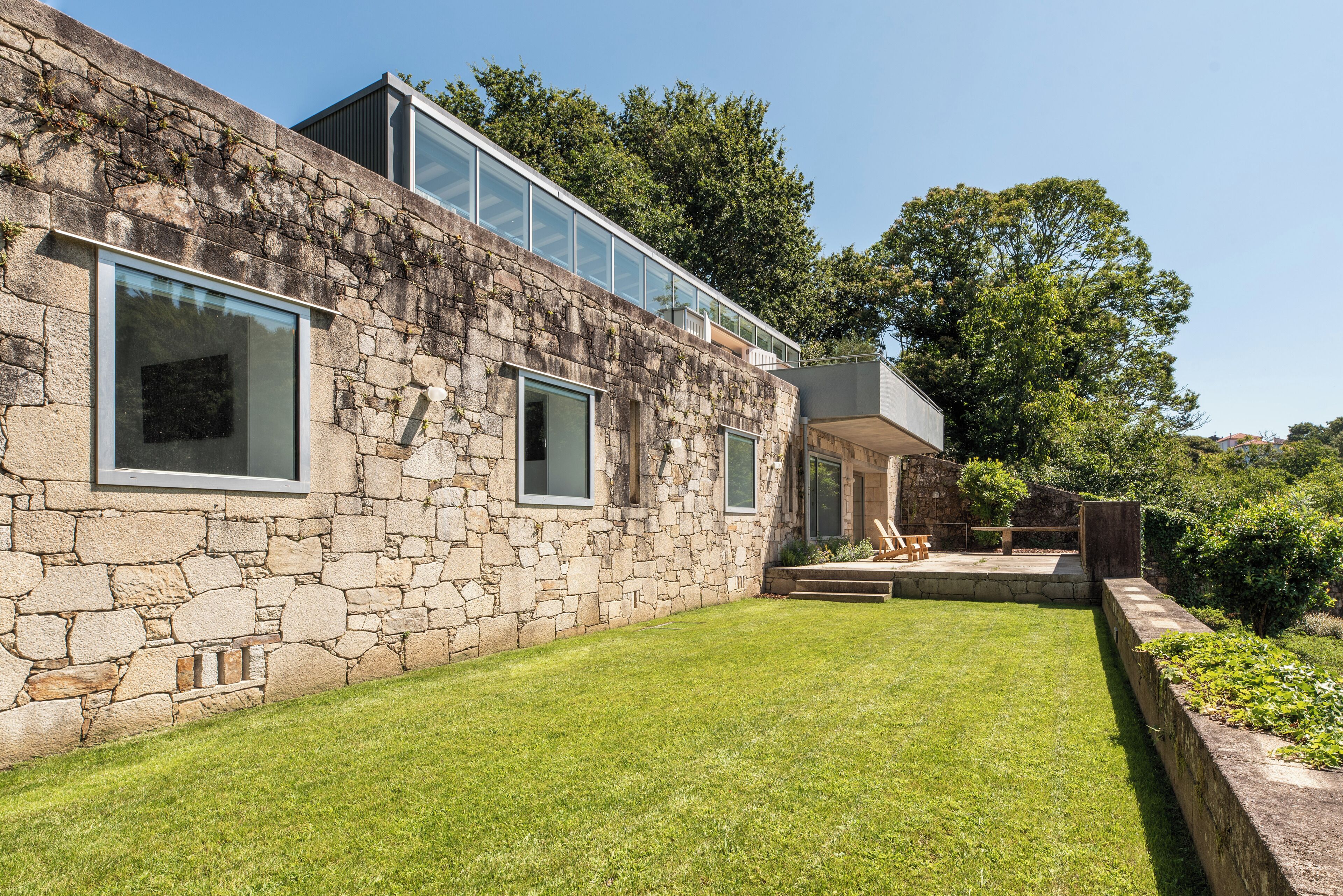 A stone building with large windows, a grassy yard, and a wooden deck.