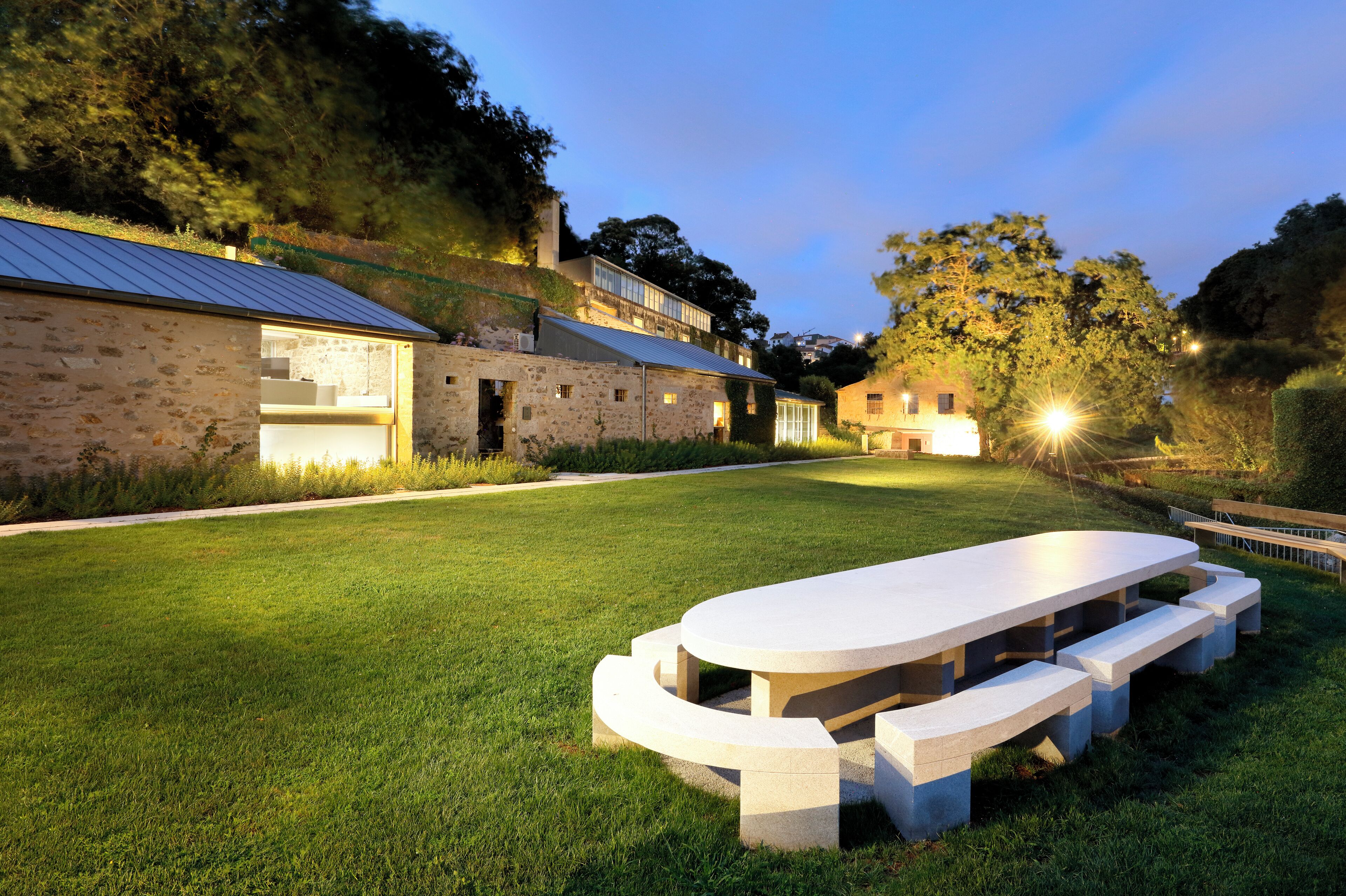Un edificio de piedra con techo plano y una amplia mesa al aire libre con bancos.