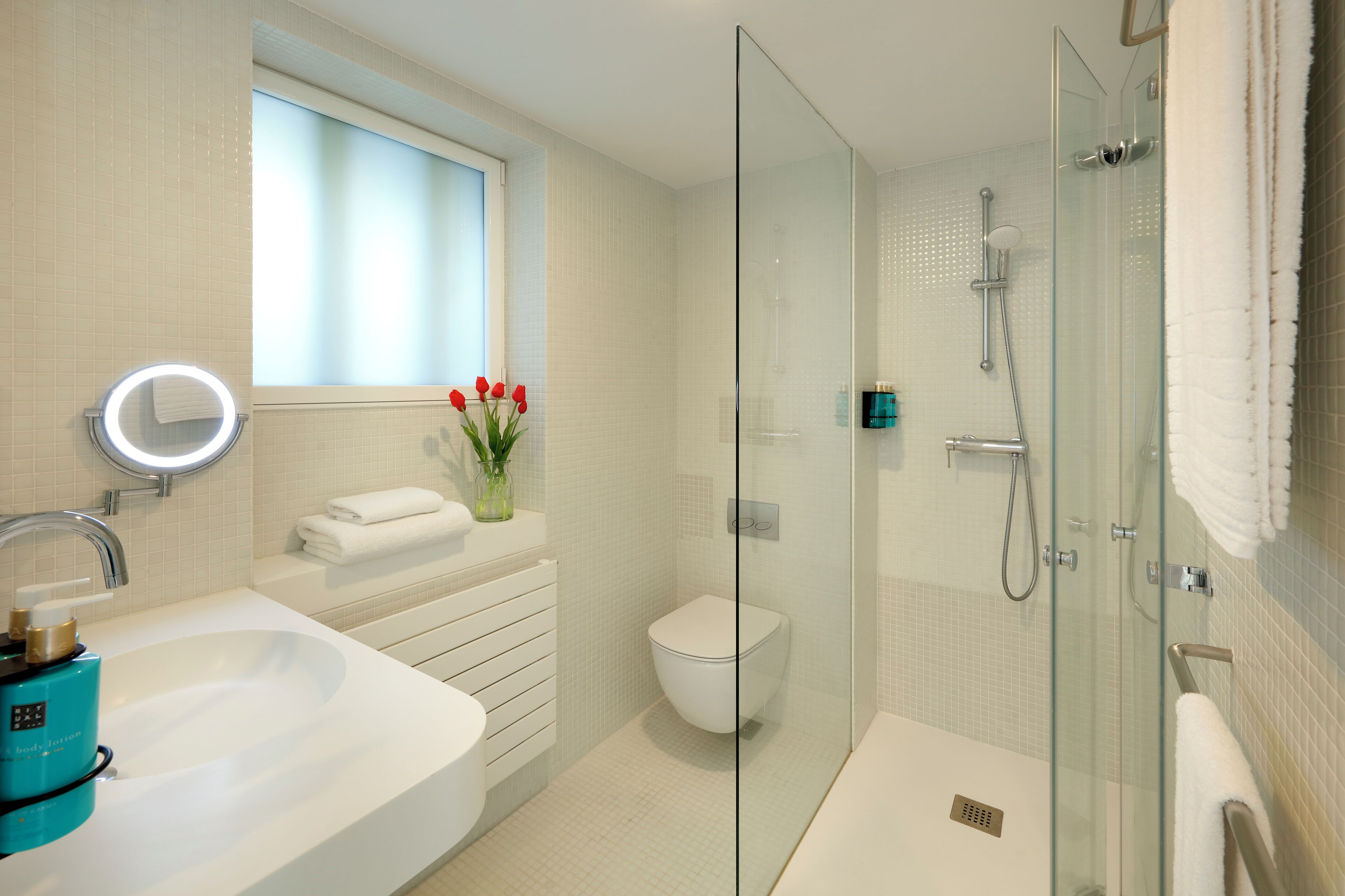 A modern bathroom with a glass-enclosed shower, a white sink, and a toilet.