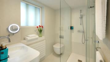 A modern bathroom with a glass-enclosed shower, a white sink, and a toilet.