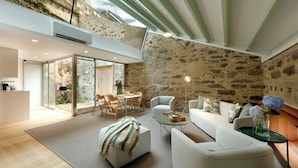 A modern living room with a stone wall, a glass door leading to an outdoor area, and a cozy seating arrangement.