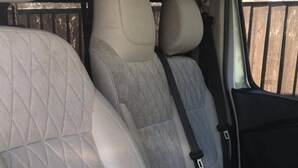 The interior of a vehicle with quilted beige seats and a black door handle. - Do not Book Unavailable (Rhyl)