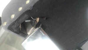 Nahaufnahme eines schwarzen Lederartikels mit Metallnieten und einem sichtbaren Schraubenkopf.