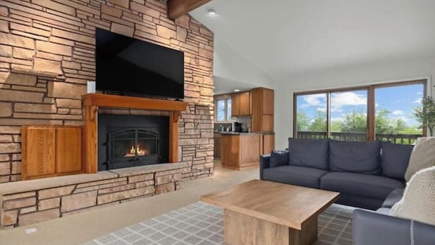 A living room with a stone fireplace, a flat-screen TV, and a sofa.