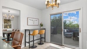 A modern kitchen with a dining area, a large sliding glass door to an outdoor deck, and a chandelier.