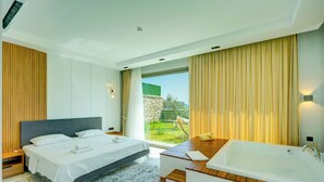 A modern bedroom with a large bed, a bathtub, and a view of a garden. - Pluto-1 PLANET LUXURY VILLAS (Kas)