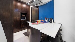 A modern kitchen with a white countertop, dark wooden cabinets, and a blue accent wall. - The House Suite Sorrento in Corso Italia  (Sorrento)