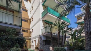 A multi-story residential building with balconies, surrounded by palm trees and potted plants. - The House Suite Sorrento in Corso Italia  (Sorrento)