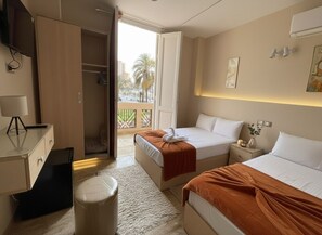 A hotel room with two beds, a desk, a chair, a small table, and a trash bin. - City Star Hotel (Cairo)