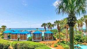 A resort with multiple blue-roofed cabanas, a pool, and palm trees. - Edgewater Tower 1-105 (Panama City Beach)