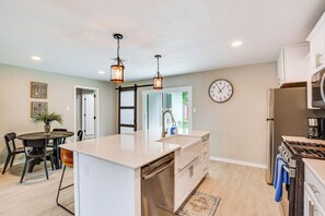 Una cocina moderna con una isla central, electrodomésticos de acero inoxidable e iluminación colgante.
