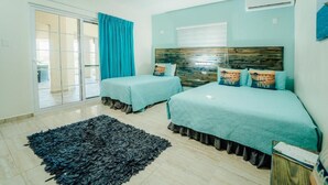 A bedroom with two beds, a large window, and a sliding door to a balcony. - Comfortable and beautiful Suite (Oranjestad)