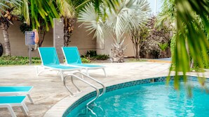 A swimming pool with blue chairs and a pool rules sign. - Comfortable and beautiful Suite (Oranjestad)