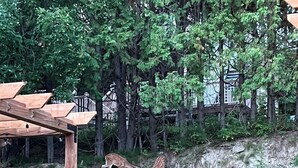 A wooden pergola structure in a landscaped garden with deer grazing, surrounded by rocks and greenery. - Modern 3-en-suite Bedroom Townhouse with 1 Sofa Bed and Terrace Mont-Tremblant (Mont-Tremblant)
