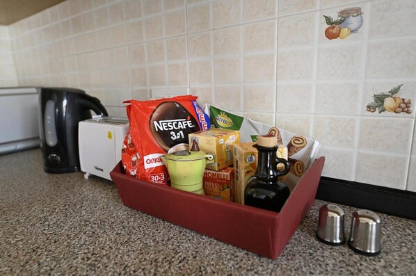A kitchen counter with a red basket containing various food items, a Nescafe coffee maker, a toaster, and a salt shaker.