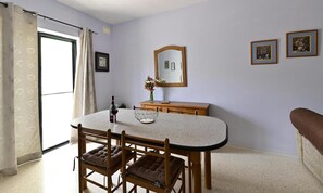 Enjoy dining and socializing in this cozy space with a round table, comfortable chairs, and a stylish vase with flowers.