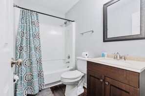A bathroom with a shower, toilet, sink, and a mirror. - Modern Private Ranch•Very Fast WiFi•Vast Fenced Yard+Big Deck+Fire Pit! (Mint Hill)