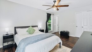 Een slaapkamer met een bed, nachtkastjes, een plafondventilator en een deur.