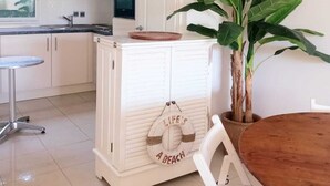 A kitchen with white cabinets, a wooden table, and a potted plant. - Pool and seaside apartment  (Cannes)