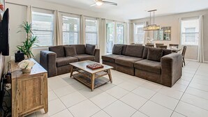 A spacious living room with two brown sofas, a wooden coffee table, and a ceiling fan. - Serene 7-Bedroom Villa in Solterra with Pool (Davenport)