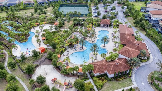 An aerial view of a resort with a large swimming pool, palm trees, and a tennis court. - Serene 7-Bedroom Villa in Solterra with Pool (Davenport)