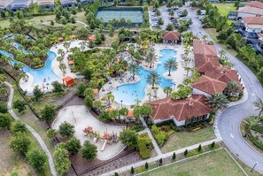 An aerial view of a resort with a large swimming pool, palm trees, and a tennis court. - Magical 7-Bedroom Villa+Pool I Water Slide (Davenport)