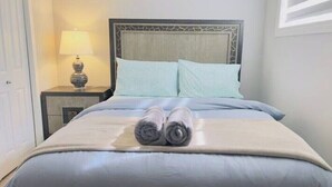Un lit bien fait, avec deux oreillers, une lampe de chevet et une serviette enroulée posée sur le lit.