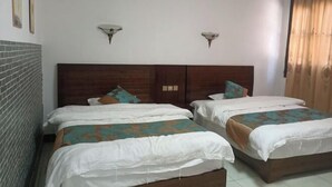 Una habitación de hotel con dos camas, una pared de ladrillo y un cabecero de madera.